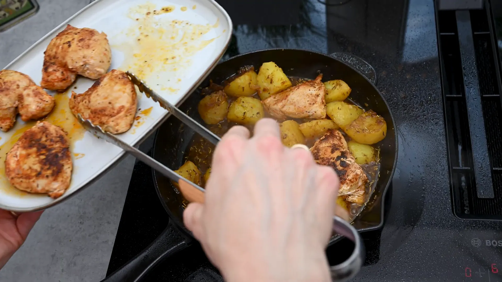 Placing chicken fillets back in the skillet with potatoes