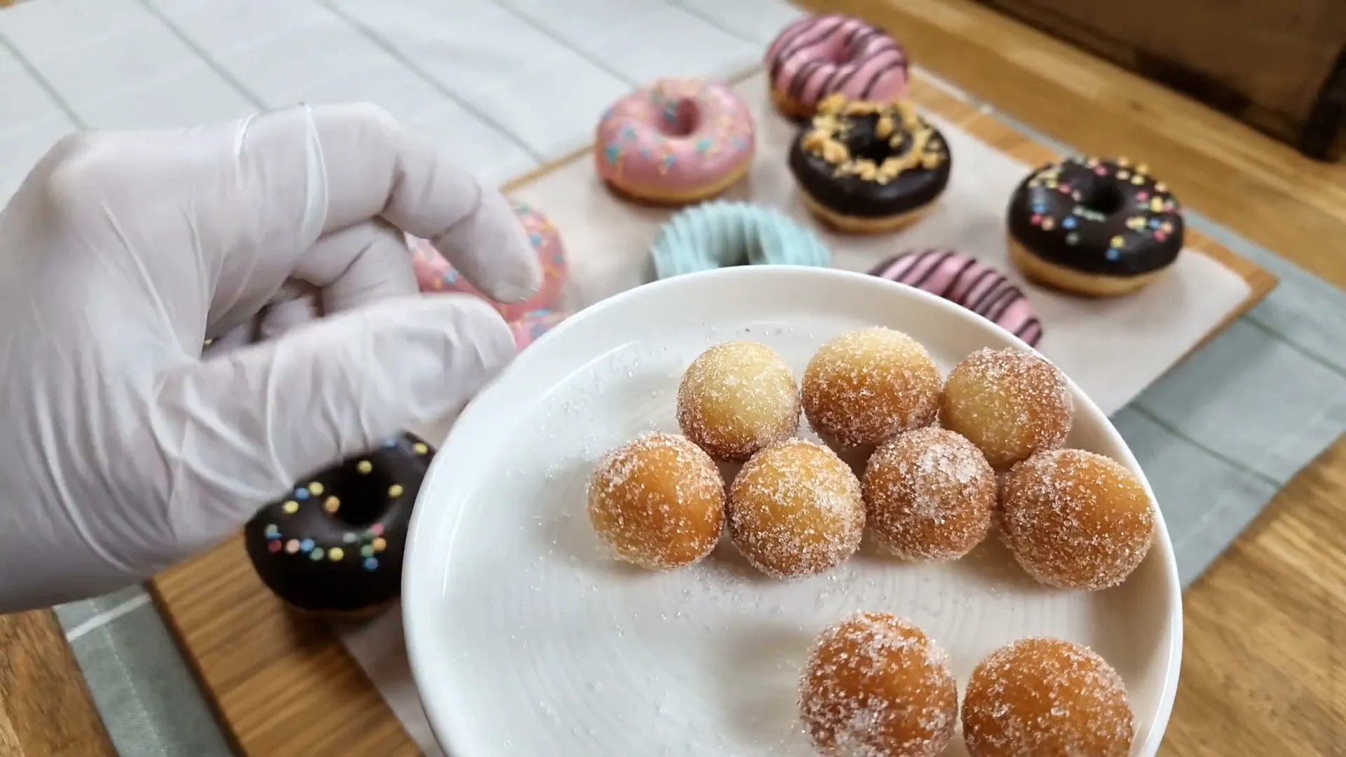 Rolling small donuts in sugar